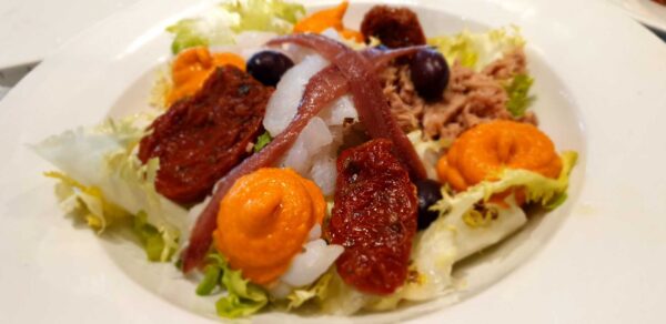 Ensañada Xato: escarola, bacalao, atún, anchoas, tomate deshidratado, aceitunas negras y salsa romesco